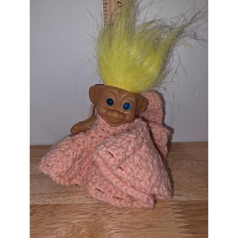 vintage plastic troll doll with bright yellow hair and blue eyes, wearing a hand